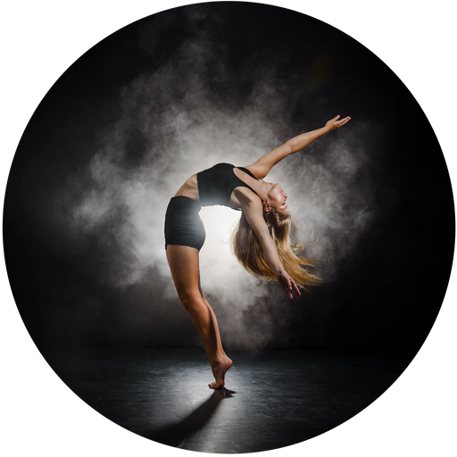 Dancer performing a pose with one arm extended against a dark background with smoke effects