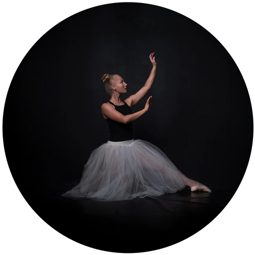 Ballerina in a black top and white tutu against a dark background