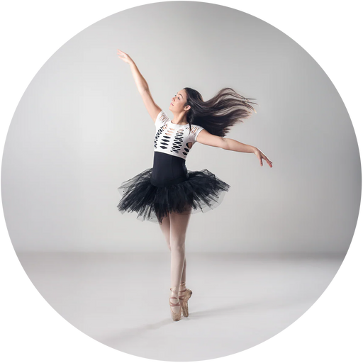 Dancer in a black tutu and white top against a gray background